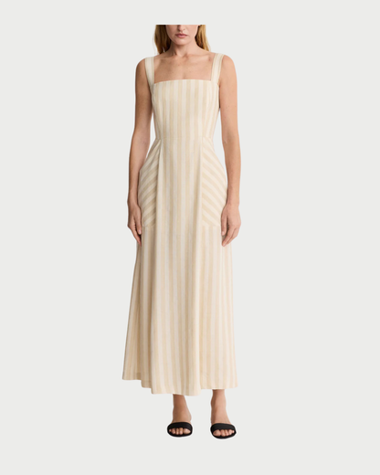 A woman models the Smythe Picnic Dress by Smythe—a beige and white striped linen midi with a square neckline, fitted bodice, and adjustable straps—against a white background, styled with black sandals for the perfect picnic look.