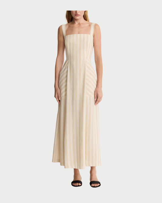 A woman models the Smythe Picnic Dress by Smythe—a beige and white striped linen midi with a square neckline, fitted bodice, and adjustable straps—against a white background, styled with black sandals for the perfect picnic look.