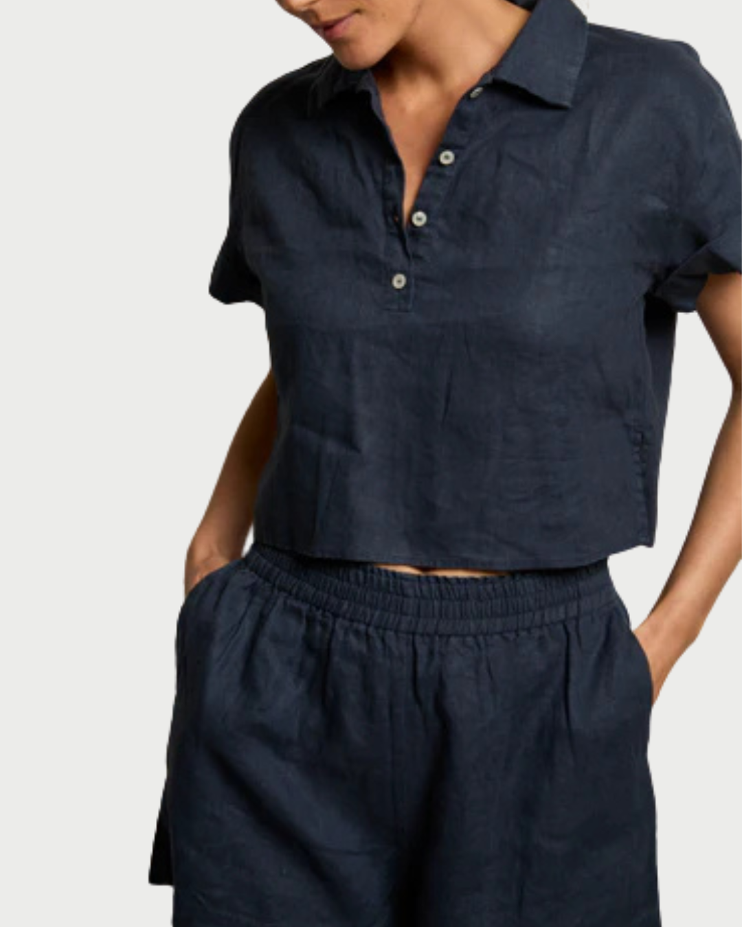 A person wears the perfectwhitetee Tabitha Buttondown Collared Tee in dark navy with matching high-waisted elastic shorts, standing with one hand in a pocket.