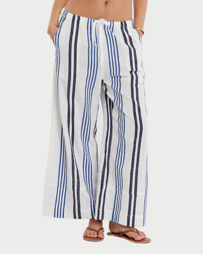 Woman wearing a blue and white striped bikini with matching pants on a white background