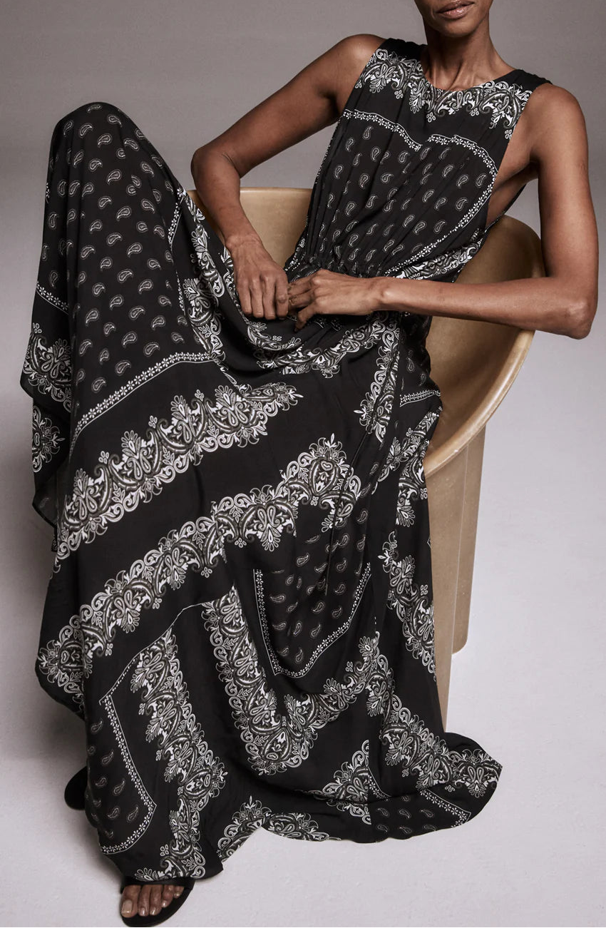 Woman wearing a black and white patterned dress sitting on a chair.