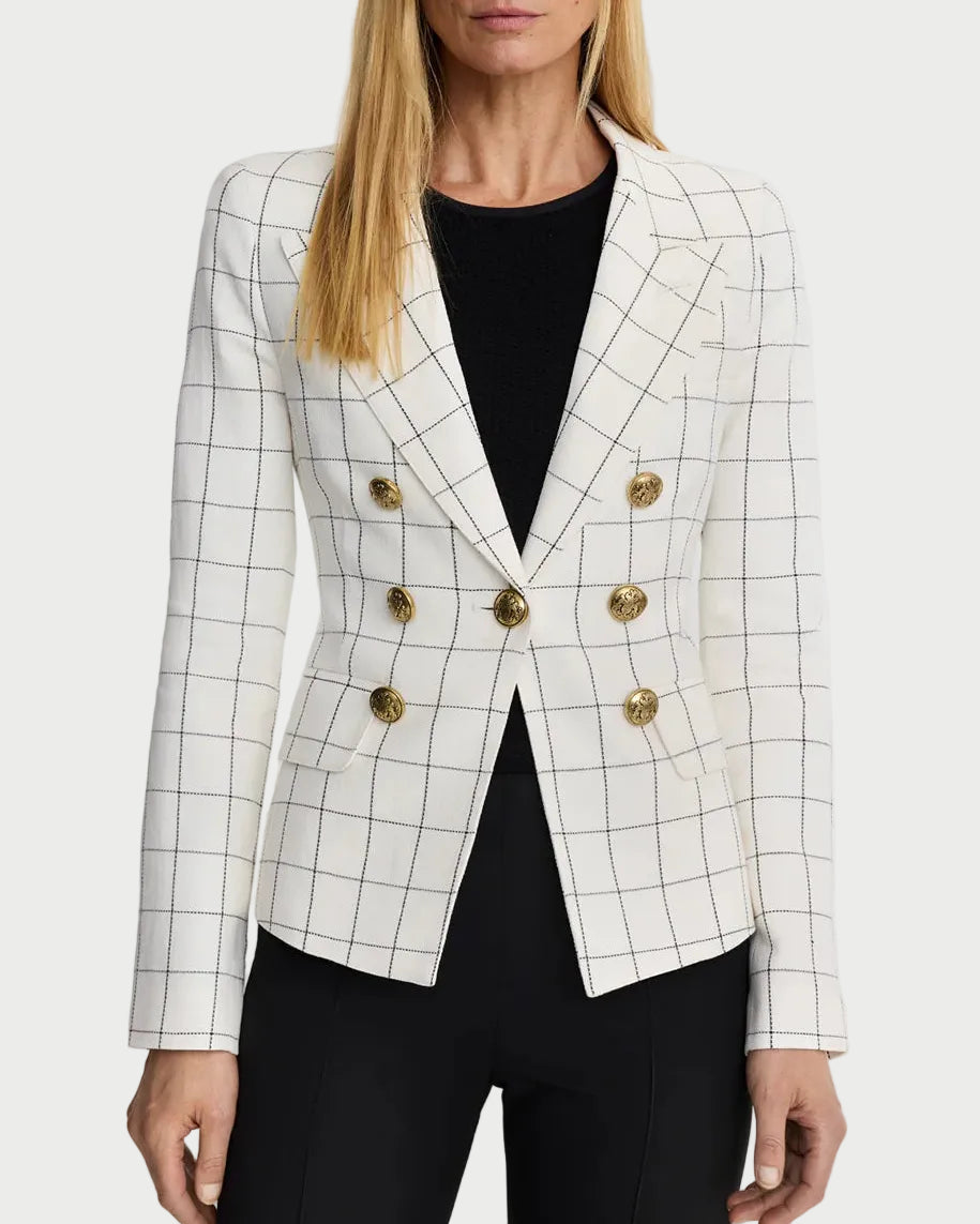 Woman wearing a white checkered blazer with gold buttons on a plain background