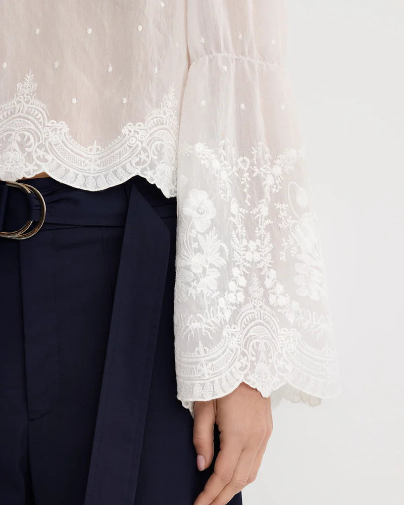 White lace top with navy pants on a white background
