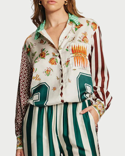 Woman wearing a patterned shirt and green and white striped pants on a plain background