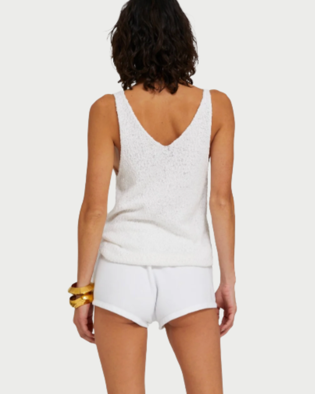 A person with short dark hair, wearing the SPRWMN Camille Top and matching shorts, stands facing away from the camera against a plain background. Gold bangles on their left wrist highlight this versatile SPRWMN wardrobe essential.