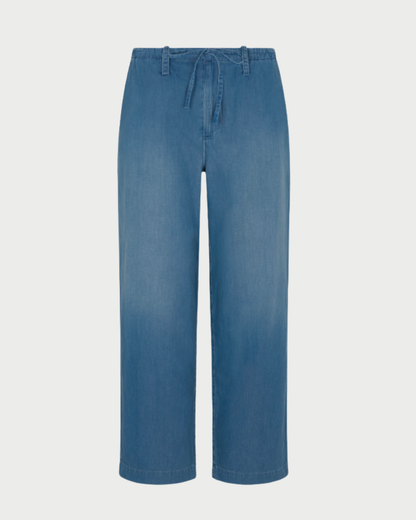 The SPRWMN Helena Drawstring Pants feature light blue chambray cotton, a relaxed straight-leg fit, elastic waistband with drawstring tie, and belt loops, displayed on a white background.
