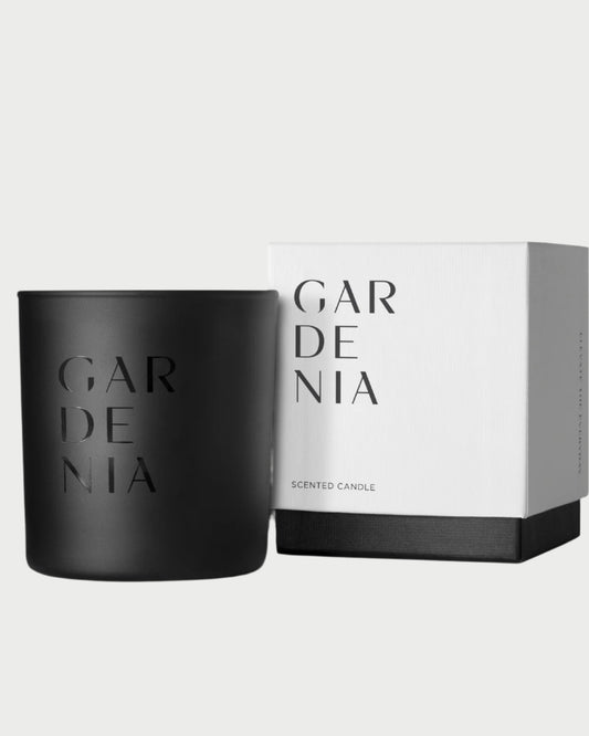 The Studio Stockhome Gardenia Candle features a black holder with "GARDENIA" cut out, paired with a sleek white box. This elegant, minimalistic set from Studio Stockhome uses natural soy for a luxurious feel and long burn time.