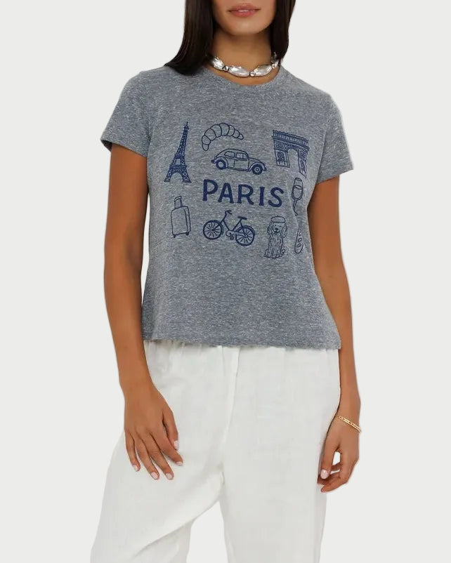 Woman wearing a gray graphic t-shirt and white pants on a plain background