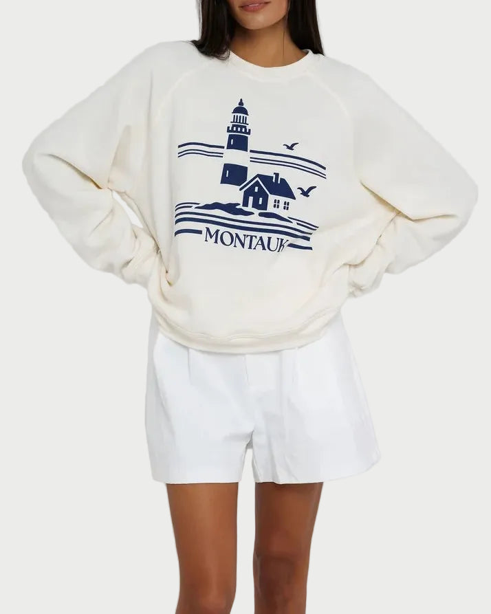 Person wearing a white sweatshirt with a graphic design on a plain background