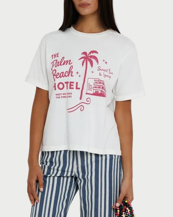 Woman wearing a white t-shirt with text and graphics, striped pants, and holding a plaid bag on a white background