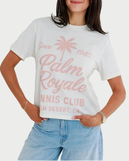 Woman wearing a 'Palm Royale' t-shirt with a white background