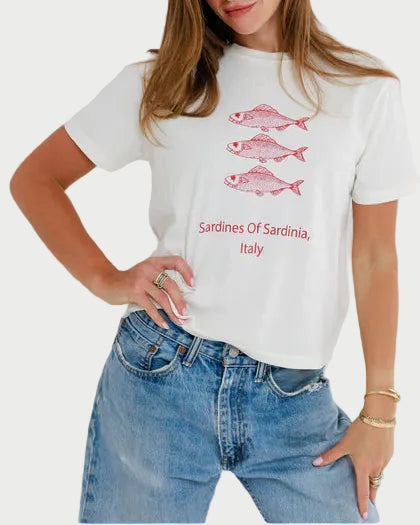 Woman wearing a white t-shirt with red fish graphics and text, standing against a plain background