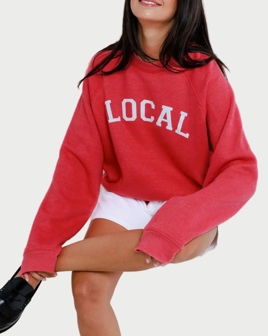 Person wearing a red 'LOCAL' sweatshirt against a white background
