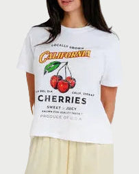 Person wearing a white t-shirt with cherry design and beige pants on a plain background