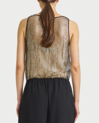 Woman wearing a patterned top and black pants on a plain background