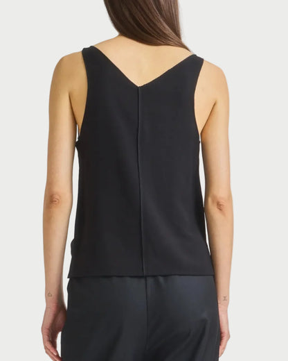 A woman with straight brown hair wears the Saint Art NY Kiera Tank in black and matching pants. She is shown from the back against a plain white background, with her arms relaxed at her sides.