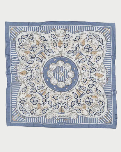 The Maison Lecomte Flament Bretagne Scarf by Maison Lecomte Flament is a square blue and white scarf with a maritime-inspired print featuring seashells, coral, paisley shapes, striped borders, and a central circular shell motif.
