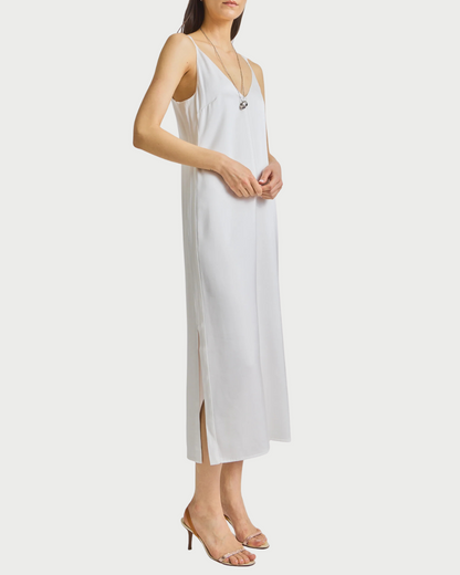 Woman wearing a white slip dress on a plain background