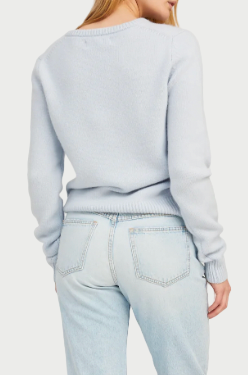 Woman wearing a light blue sweater and jeans on a white background