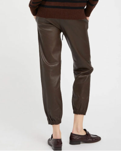 A person is seen from the back wearing SPRWMN Leather Drawstring Jogger pants in dark brown lambskin with brown loafers, standing against a plain white background.