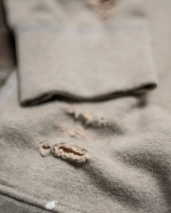 Close-up of a worn-out gray shirt with visible damage.