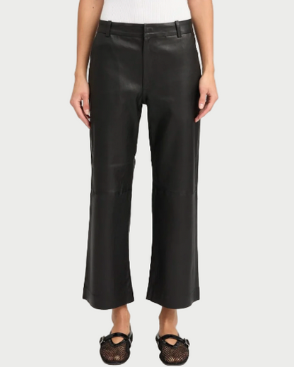 A person stands facing forward against a plain background, wearing SPRWMN Cropped Leather Trousers, a white sleeveless top, and black mesh ballet flats.