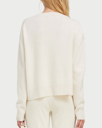 Person wearing a cream-colored outfit holding a matching tote bag on a white background