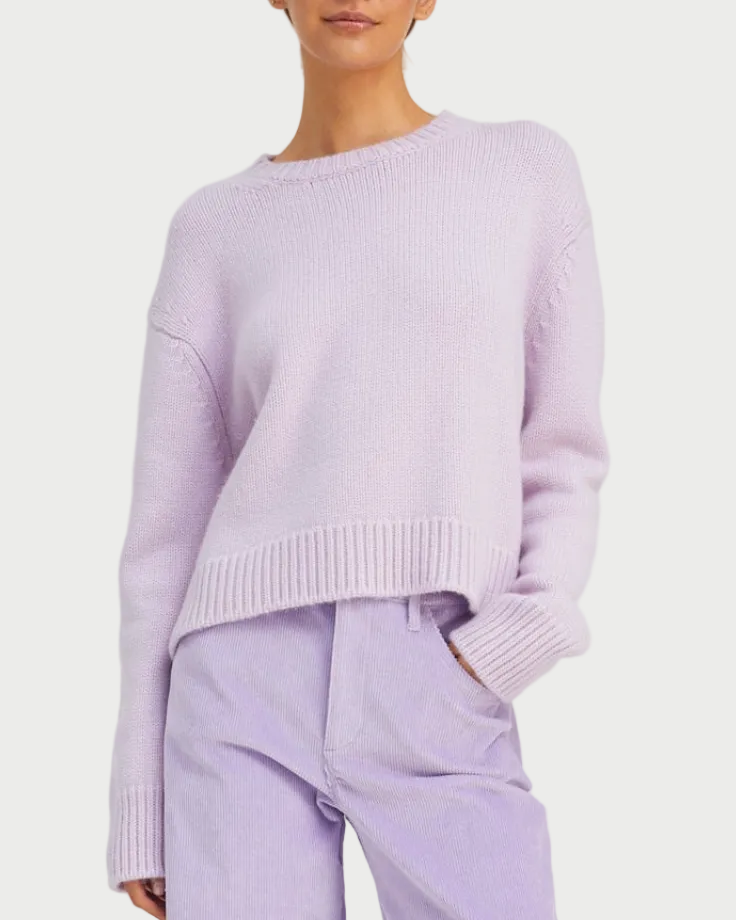A person wears the SPRWMN Heavy Cashmere Crew in light purple by SPRWMN, paired with matching lavender pants, one hand in their pocket, shown from the chest down against a white background.