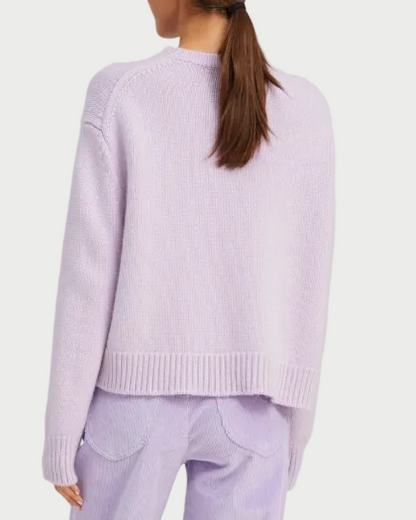 A woman with brown hair in a ponytail is shown from the back, wearing the SPRWMN Heavy Cashmere Crew sweater by SPRWMN in light purple, paired with matching light purple corduroy pants.
