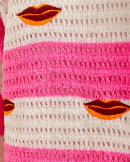 Close-up of a textured fabric with pink and white stripes and orange lips design.
