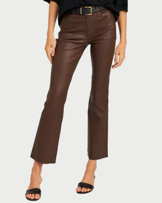 A person wears SPRWMN 5 Pocket Ankle Flare pants—high-waisted dark brown French lambskin leather—styled with a black belt, black top, and black open-toe sandals. Only the lower half of the body is shown against a plain background.