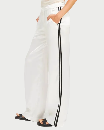 Woman wearing a white sleeveless top and wide-leg pants with a side stripe on a white background