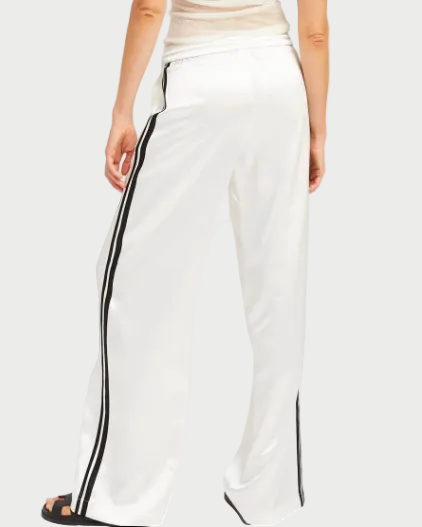 Woman wearing a white sleeveless top and wide-leg pants with a black stripe on a white background