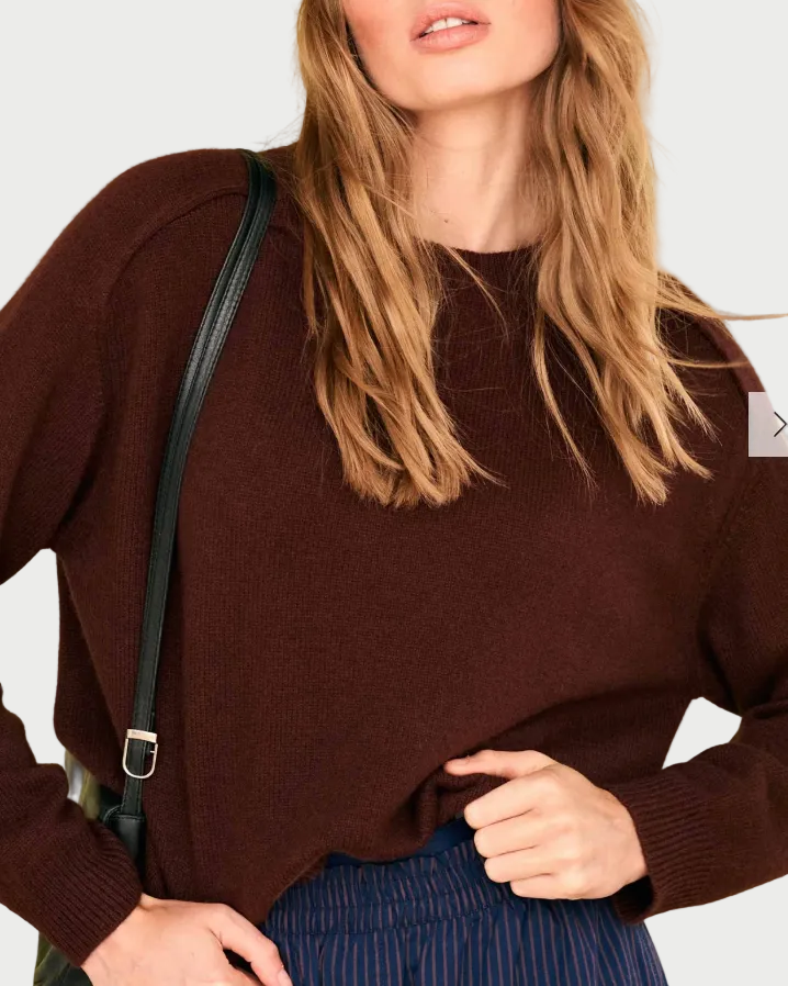 Person wearing an oversized, dark brown JUMPER1234 Oversize Cashmere Crew Cocoa sweater with a black shoulder bag strap.