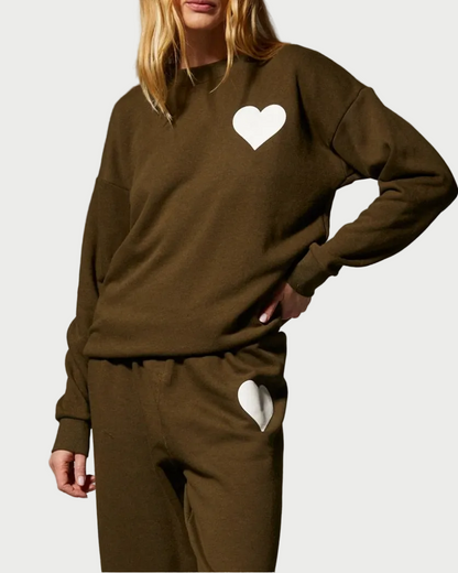 Olive green sweatshirt and matching SPRWMN Heart Sweatpants, each featuring a white heart patch on the upper chest and hip.