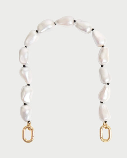The CLARE V. Shortie Strap In Pearl is a decorative bag strap with irregular white pearls and black pearlized wood beads, finished with gold clasps at each end, shown against a plain light background.