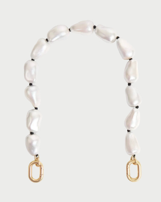 The CLARE V. Shortie Strap In Pearl is a decorative bag strap with irregular white pearls and black pearlized wood beads, finished with gold clasps at each end, shown against a plain light background.