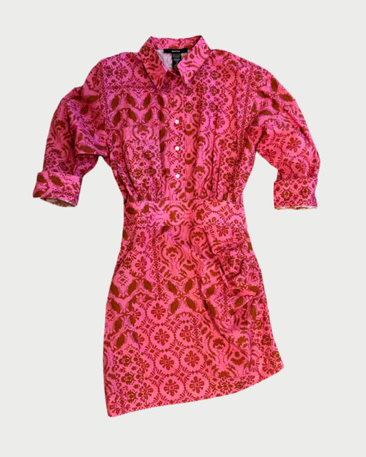 The Smythe Mini Shirt Dress features long sleeves, a button-up front, a collared neckline, a pink and red floral print, and a matching fabric belt at the waist.