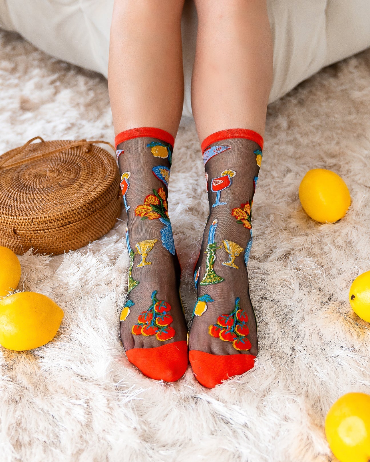Person wearing sheer socks with colorful designs on a fluffy white surface.