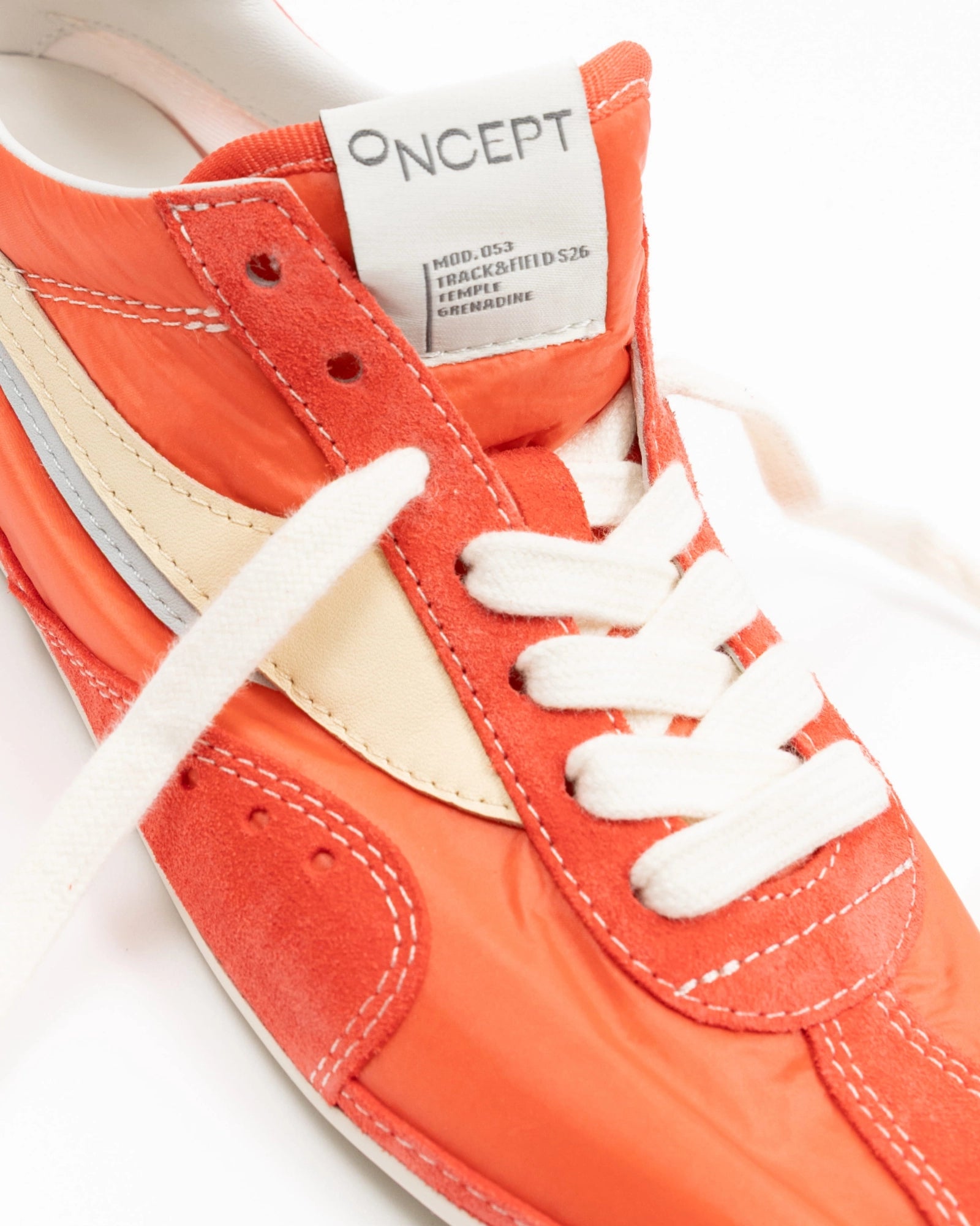 Close-up of an orange sneaker with white laces and 'ONCEPT' label on a white background
