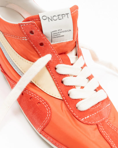 Close-up of an orange sneaker with white laces and 'ONCEPT' label on a white background