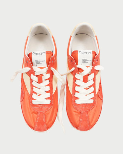 A pair of Oncept Temple Sneakers in Grenadine, featuring bright orange and white panels with white laces, viewed from above on a white background. The insoles display the "ONCEPT" logo in black. Sustainable design combines style and comfort.