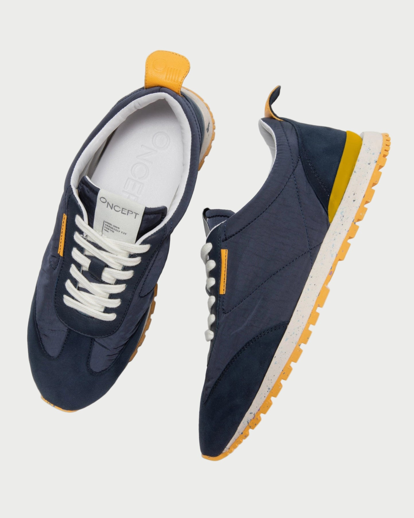 Navy blue sneakers with yellow accents on a white background