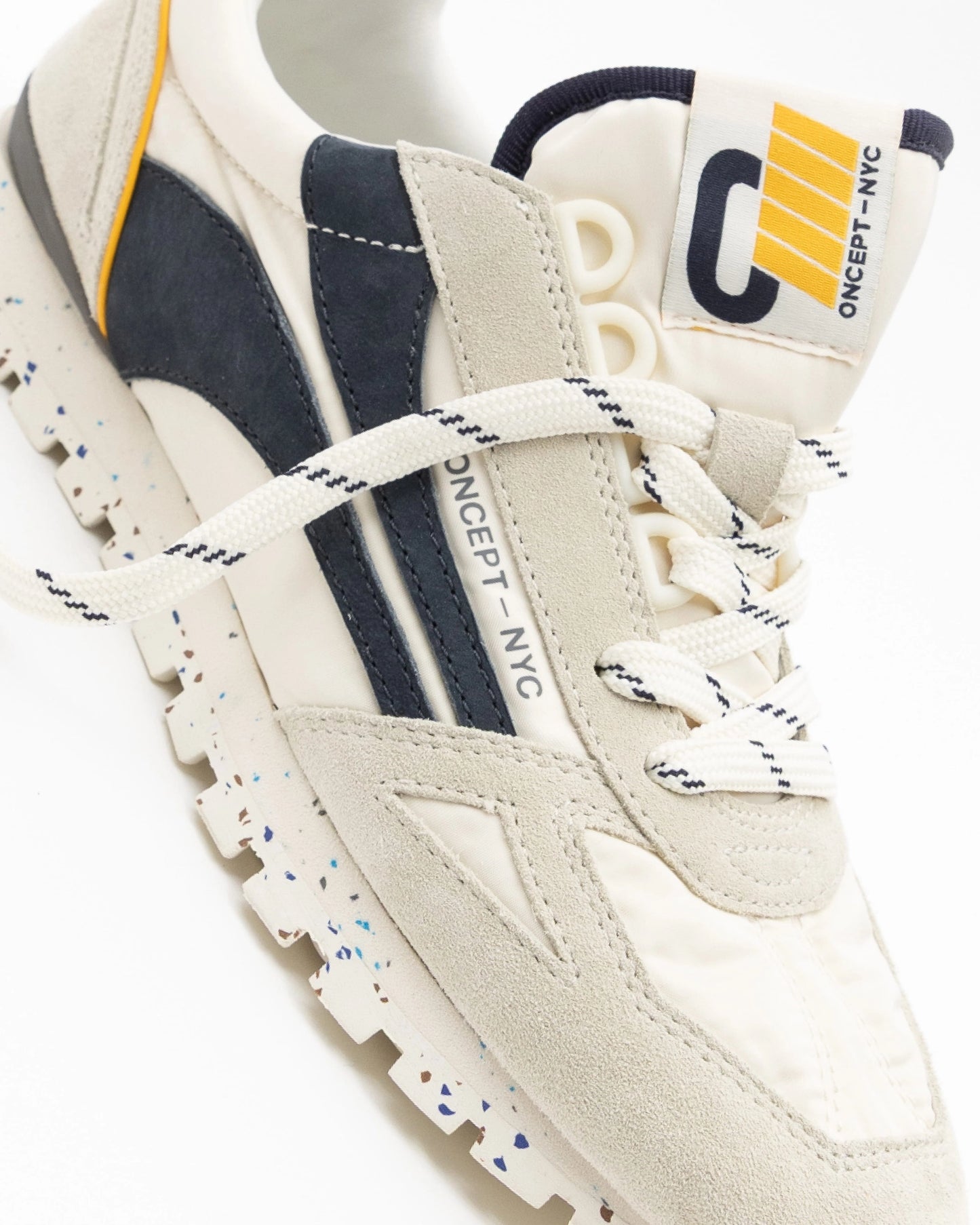 White sneaker with navy accents and brand logo on a white background