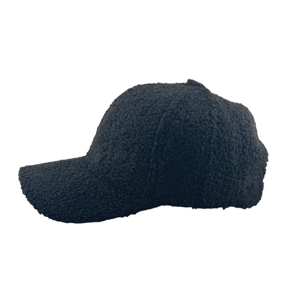 This comfortable Teddy Trucker Hat by Soulbyrd, featuring a black textured baseball cap with a curly, fleece-like material, is elegantly showcased in profile on a plain white background, capturing the essence of Soulbyrd LA's iconic style.