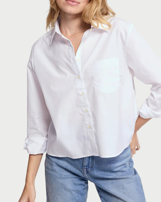 Woman wearing a white shirt and blue jeans against a plain background