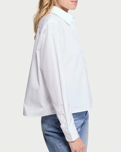 Woman wearing a white blouse and blue jeans on a plain background