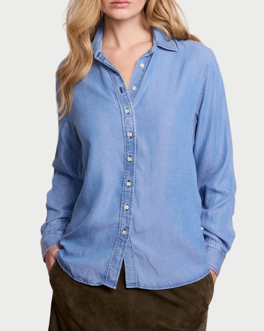Woman wearing a light blue denim shirt against a plain background