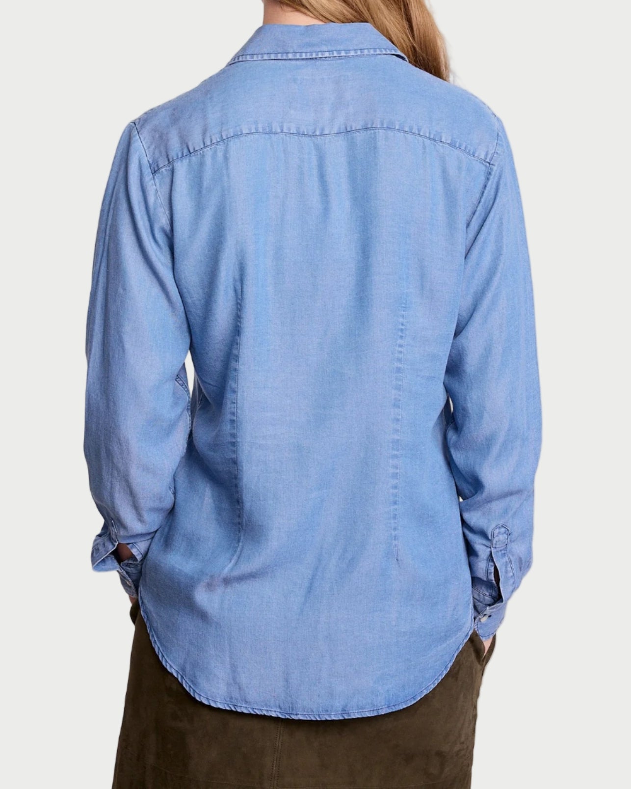Person wearing a blue denim shirt against a plain background
