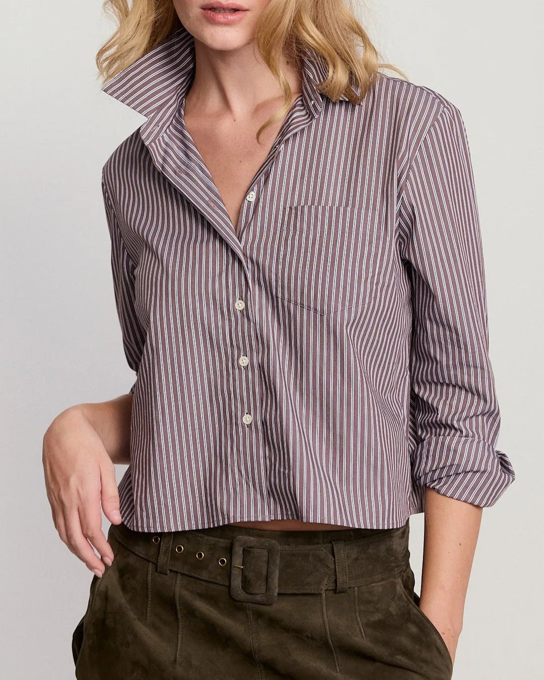 Woman wearing a striped shirt and dark pants on a plain background